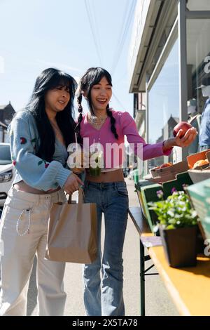 Giovani donne che comprano frutta per strada Foto Stock