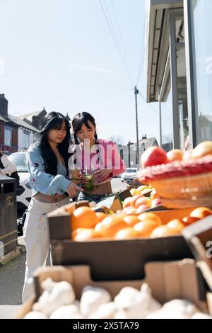 Giovani donne che comprano frutta per strada Foto Stock