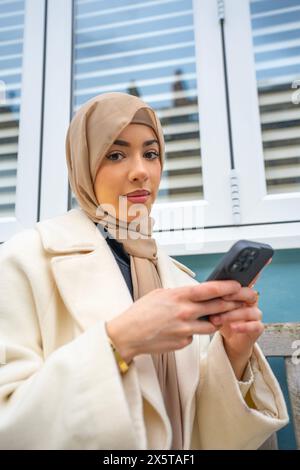 Ritratto di una giovane donna che indossa hijab usando il telefono Foto Stock