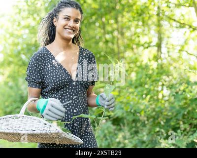 Ritratto di donna che raccoglie fiori nel cestino Foto Stock