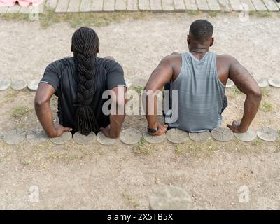 Due uomini che fanno i triceps immergono all'aperto Foto Stock