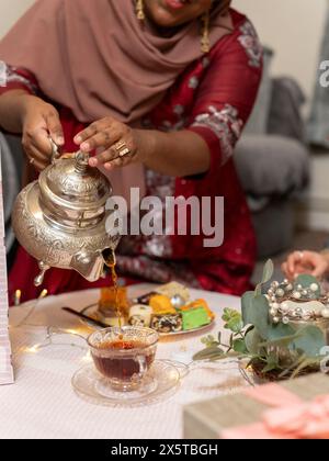 Donna che versa il tè durante la celebrazione del Ramadan a casa Foto Stock