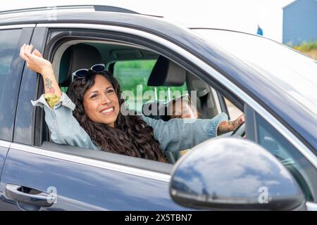 Madre sorridente che guida un'auto con figlia addormentata (8-9) Foto Stock