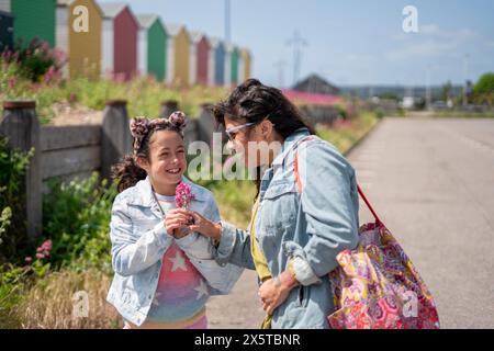 Madre sorridente e figlia (8-9) in possesso di fiori Foto Stock