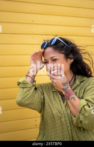 Donna sorridente in mezza età con tatuaggi e occhiali da sole Foto Stock