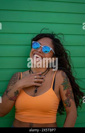 Donna sorridente in mezza età con tatuaggi e occhiali da sole Foto Stock