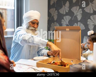 Famiglia di tre generazioni (6-7) che mangia pizza a casa Foto Stock