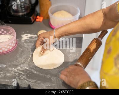 Primo piano di una donna che arrotola l'impasto in cucina Foto Stock