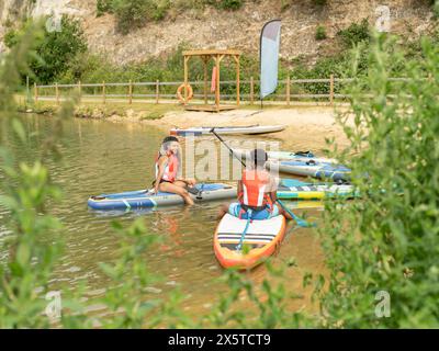 Amici che si rilassano in paddleboard sul lago Foto Stock