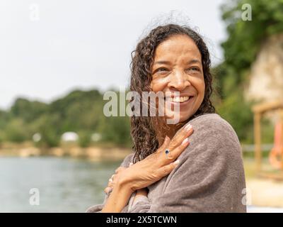 Ritratto di donna sorridente avvolto in un asciugamano sul lago Foto Stock