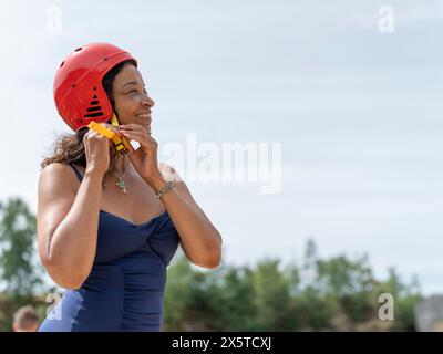 Donna sorridente che indossa un casco sportivo Foto Stock