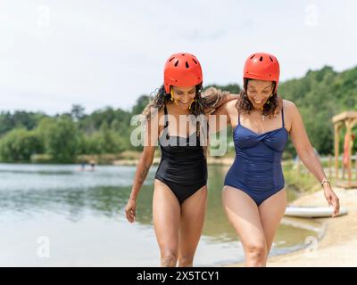 Donne che camminano con i caschi sportivi sul lago Foto Stock