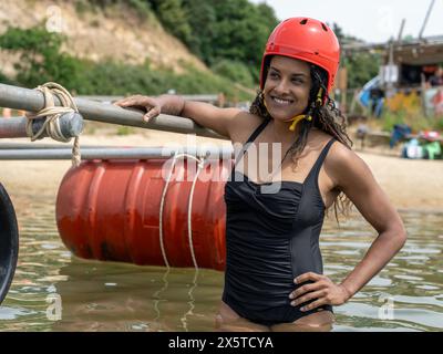 Ritratto di donna sorridente con zattera in legno nel lago Foto Stock