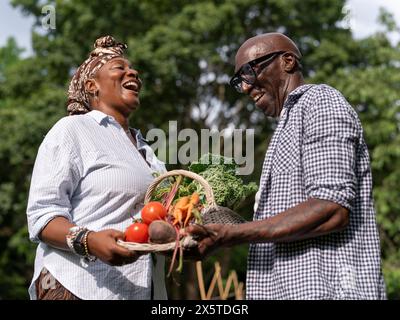 Una coppia matura sorridente che tiene le verdure dall'orto Foto Stock