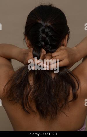 Vista posteriore della donna che intreccia i capelli Foto Stock