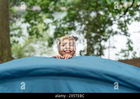 Donna sorridente che mette una tenda nella foresta Foto Stock