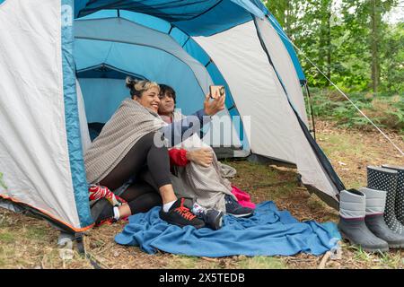 Madre e figlio si fanno selfie in tenda Foto Stock