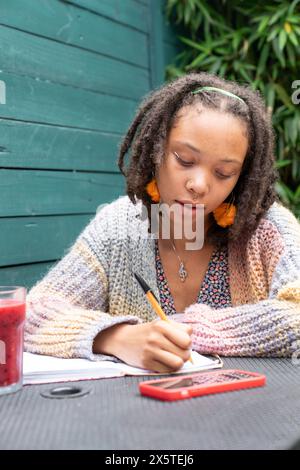 Giovane donna che scrive diario in giardino Foto Stock