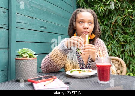 Giovane donna che pranza in giardino Foto Stock