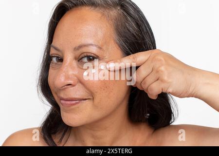 Ritratto in studio di una donna sorridente con puntini di crema per gli occhi Foto Stock