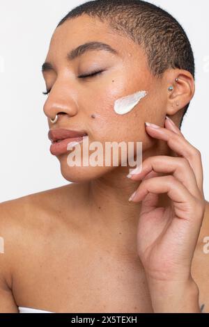 Ritratto in studio di una donna con la panna sulla guancia Foto Stock