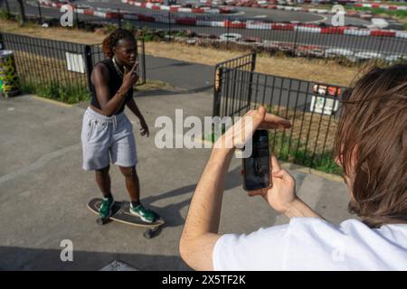 Uomo che fotografa un'amica donna sullo skateboard Foto Stock