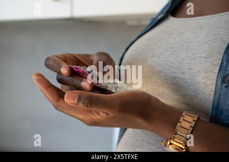 Primo piano di una donna incinta che tiene le capsule Foto Stock