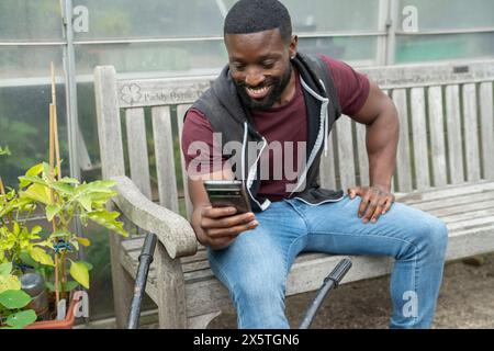 Uomo sorridente che fotografa verdure con lo smartphone Foto Stock