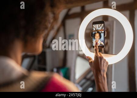 Donna che registra video con uno smartphone a casa Foto Stock