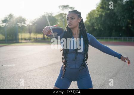 Atleta che allena il lancio di un disco allo stadio Foto Stock