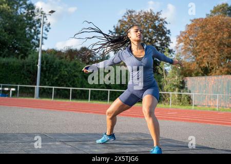 Atleta che allena il lancio di un disco allo stadio Foto Stock