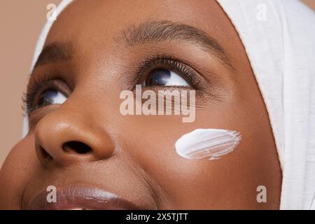 Foto di studio di una giovane donna in hijab bianco che applica la crema per il viso Foto Stock