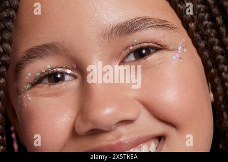 Primo piano di una ragazza sorridente con adesivi decorativi sul viso Foto Stock