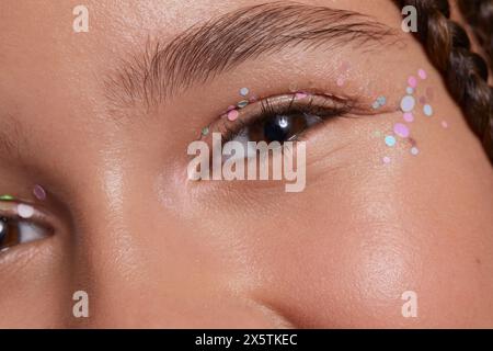 Primo piano di una ragazza sorridente con adesivi decorativi sul viso Foto Stock