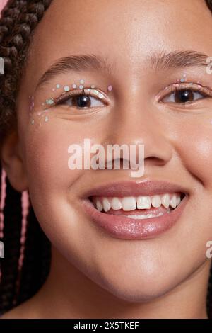 Primo piano di una ragazza sorridente con adesivi decorativi sul viso Foto Stock