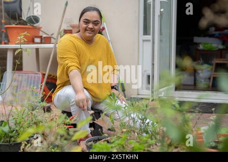 Ritratto di giovane donna con sindrome di Down che piantano fiori in giardino Foto Stock