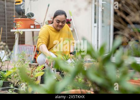 Giovane donna con sindrome di Down che piantano fiori in giardino Foto Stock