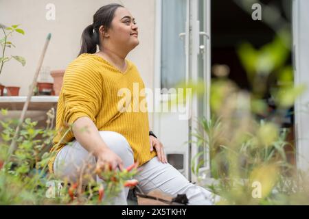 Giovane donna con sindrome di Down che piantano fiori in giardino Foto Stock