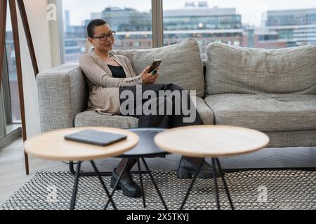 Persona non binaria che riposa nella hall dell'ufficio Foto Stock