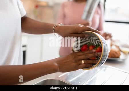 Primo piano di una donna che lava le fragole in cucina Foto Stock