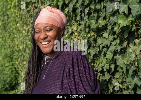 Ritratto di una bella donna con dreadlock davanti al muro dell'edera Foto Stock