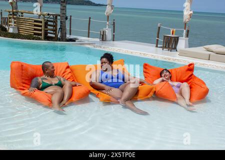 Gruppo di donne allegre che si rilassano sulle zattere della piscina in piscina Foto Stock