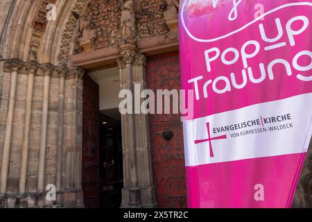 11 maggio 2024, Assia, Marburgo: "Matrimoni pop-up" è scritto su uno striscione di fronte alla Chiesa protestante di Elisabetta, dove le cerimonie nuziali o i matrimoni benedetti sono resi possibili a tutte le coppie il sabato, con o senza previa registrazione. Almeno 24 coppie hanno ricevuto la benedizione di Dio sull'altare da una squadra di pastori protestanti nella Chiesa di Santa Elisabetta e nella Cappella di San Michele di fronte - senza complicazioni e senza mesi di preparazione. Foto: Christian Lademann/dpa - ATTENZIONE: Solo per uso editoriale in relazione a un rapporto e solo con menzione completa dei suddetti credi Foto Stock