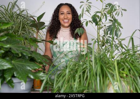 Ritratto in studio di una donna sorridente circondata da piante in vaso Foto Stock