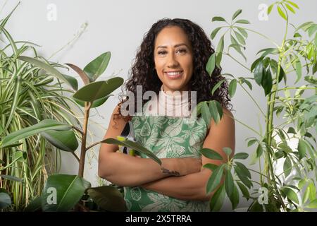 Ritratto in studio di una donna sorridente circondata da piante in vaso Foto Stock