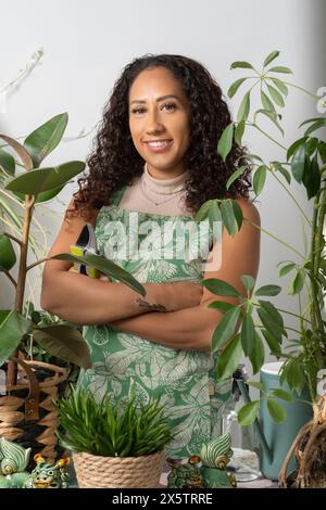 Ritratto in studio di una donna sorridente circondata da piante in vaso Foto Stock