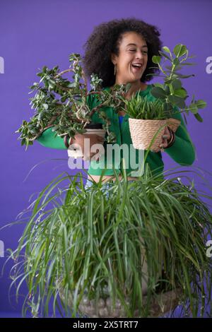 Ritratto in studio di una donna sorridente che tiene le piante in vaso Foto Stock