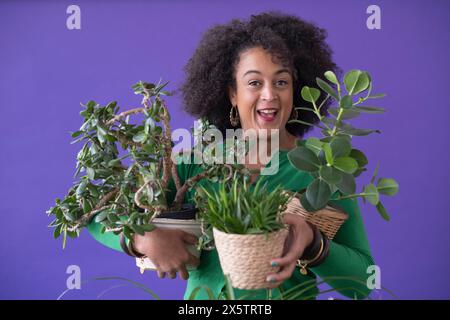 Ritratto in studio di una donna sorridente che tiene le piante in vaso Foto Stock