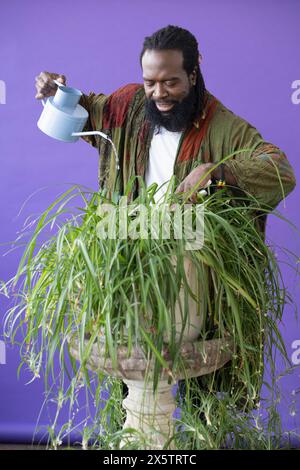 Ritratto in studio di un uomo che innaffiava una pianta in vaso Foto Stock