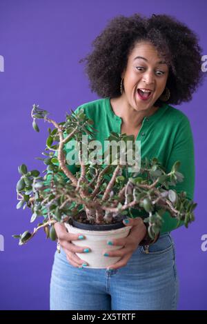 Ritratto in studio di una donna sorridente che tiene una pianta in vaso Foto Stock